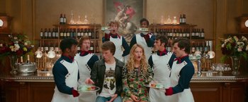 Movie still from “Mamma Mia! Here We Go Again” (2018), directed by Ol Parker – A group of people standing in front of a painting; Medium shot, Over the shoulder angle