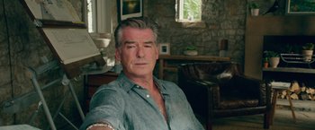 Movie still from “Mamma Mia! Here We Go Again” (2018), directed by Ol Parker – A man sitting in a chair in a living room; Close Up shot, Over the shoulder angle