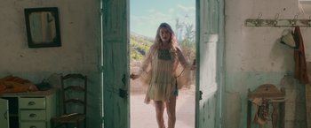 Movie still from “Mamma Mia! Here We Go Again” (2018), directed by Ol Parker – A woman in a dress standing in front of an open door; Medium shot, Low angle