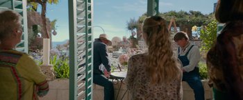 Movie still from “Mamma Mia! Here We Go Again” (2018), directed by Ol Parker – A man and a woman standing at an outdoor table; Medium shot, Over the shoulder angle