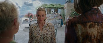 Movie still from “Mamma Mia! Here We Go Again” (2018), directed by Ol Parker – A woman standing in front of a bunch of tables; Medium shot, Over the shoulder angle