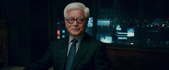 Movie still from “Mamma Mia! Here We Go Again” (2018), directed by Ol Parker – An older man wearing a suit and tie; Close Up shot, Over the shoulder angle