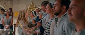 Movie still from “Mamma Mia! Here We Go Again” (2018), directed by Ol Parker – A group of people standing around each other; Medium shot, Over the shoulder angle