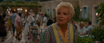 Movie still from “Mamma Mia! Here We Go Again” (2018), directed by Ol Parker – An older woman with blonde hair wearing a multicolored dress; Close Up shot, Over the shoulder angle