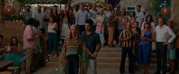 Movie still from “Mamma Mia! Here We Go Again” (2018), directed by Ol Parker – A group of people standing on steps in front of a crowd; Wide shot, High angle