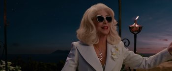 Movie still from “Mamma Mia! Here We Go Again” (2018), directed by Ol Parker – An older woman wearing sunglasses and a white jacket; Close Up shot, Over the shoulder angle