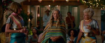 Movie still from “Mamma Mia! Here We Go Again” (2018), directed by Ol Parker – A woman standing in front of a group of people; Medium shot, Over the shoulder angle