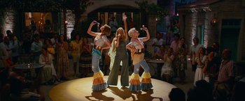 Movie still from “Mamma Mia! Here We Go Again” (2018), directed by Ol Parker – A group of women performing on a stage; Wide shot, High angle
