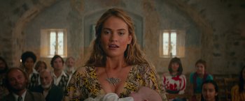 Movie still from “Mamma Mia! Here We Go Again” (2018), directed by Ol Parker – A woman holding a baby in a room with ornate walls; Close Up shot, Over the shoulder angle