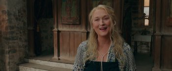 Movie still from “Mamma Mia! Here We Go Again” (2018), directed by Ol Parker – A woman with long blonde hair smiling for the camera; Close Up shot, Over the shoulder angle