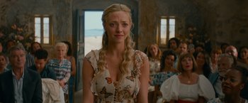 Movie still from “Mamma Mia! Here We Go Again” (2018), directed by Ol Parker – A woman with long blonde hair standing in front of a group of people; Close Up shot, Over the shoulder angle
