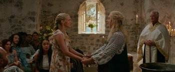 Movie still from “Mamma Mia! Here We Go Again” (2018), directed by Ol Parker – Two women are holding hands in front of a window; Medium shot, Over the shoulder angle