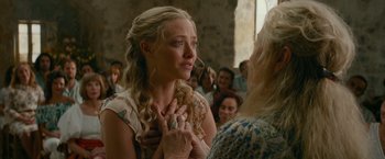 Movie still from “Mamma Mia! Here We Go Again” (2018), directed by Ol Parker – A woman with long blonde hair is holding her face; Close Up shot, Over the shoulder angle