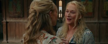 Movie still from “Mamma Mia! Here We Go Again” (2018), directed by Ol Parker – Two women talking to each other in front of a building; Close Up shot, Over the shoulder angle