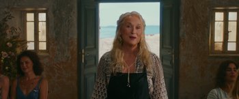 Movie still from “Mamma Mia! Here We Go Again” (2018), directed by Ol Parker – A woman standing in front of an open door; Medium shot, Over the shoulder angle