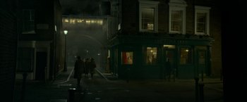 Movie still from “Mrs. Harris Goes to Paris” (2022), directed by Anthony Fabian – People walking down a street at night in the dark; Extreme Wide shot, High angle