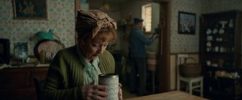 Movie still from “Mrs. Harris Goes to Paris” (2022), directed by Anthony Fabian – An older woman is holding a coffee mug; Medium shot, Over the shoulder angle