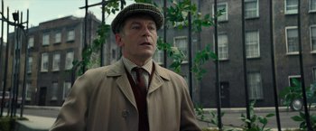 Movie still from “Mrs. Harris Goes to Paris” (2022), directed by Anthony Fabian – A man wearing a hat and a coat; Close Up shot, Low angle