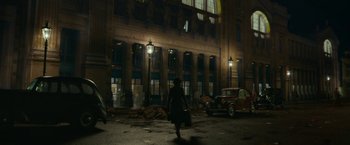 Movie still from “Mrs. Harris Goes to Paris” (2022), directed by Anthony Fabian – A woman walking down the street at night with a suitcase; Extreme Wide shot, High angle