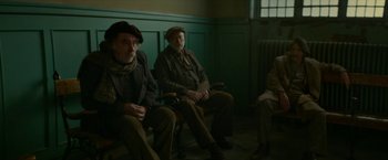 Movie still from “Mrs. Harris Goes to Paris” (2022), directed by Anthony Fabian – A group of men sitting on a bench; Medium shot, High angle