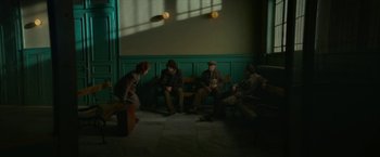 Movie still from “Mrs. Harris Goes to Paris” (2022), directed by Anthony Fabian – A group of people sitting on top of a wooden bench; Wide shot, High angle