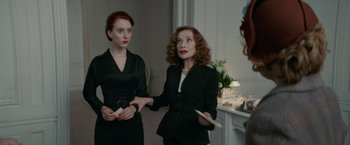 Movie still from “Mrs. Harris Goes to Paris” (2022), directed by Anthony Fabian – Two women in black suits stand next to each other in a room; Medium shot, Over the shoulder angle