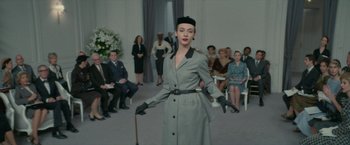 Movie still from “Mrs. Harris Goes to Paris” (2022), directed by Anthony Fabian – A woman in a gray coat and hat holding a cane; Wide shot, Low angle