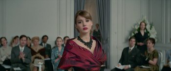 Movie still from “Mrs. Harris Goes to Paris” (2022), directed by Anthony Fabian – A woman in a red dress is posing for a picture; Close Up shot, Over the shoulder angle