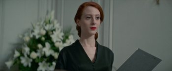 Movie still from “Mrs. Harris Goes to Paris” (2022), directed by Anthony Fabian – A woman with red hair is standing in front of a mirror; Close Up shot, Over the shoulder angle