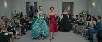 Movie still from “Mrs. Harris Goes to Paris” (2022), directed by Anthony Fabian – A group of women walking down a runway in formal wear; Wide shot, Low angle