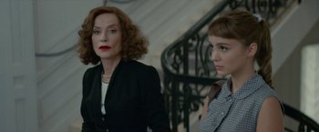 Movie still from “Mrs. Harris Goes to Paris” (2022), directed by Anthony Fabian – A woman standing next to a young girl in front of a staircase; Medium shot, Over the shoulder angle