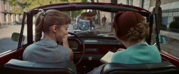 Movie still from “Mrs. Harris Goes to Paris” (2022), directed by Anthony Fabian – Two women sitting in the back seat of a car; Medium shot, Over the shoulder angle