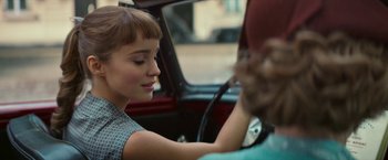 Movie still from “Mrs. Harris Goes to Paris” (2022), directed by Anthony Fabian – A woman sitting in the driver's seat of a car; Close Up shot, Over the shoulder angle