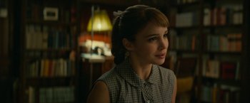 Movie still from “Mrs. Harris Goes to Paris” (2022), directed by Anthony Fabian – A young woman in a plaid shirt looking to her left; Close Up shot, Over the shoulder angle
