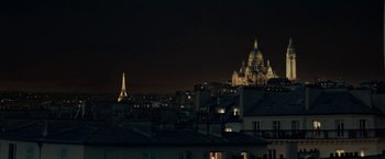 Movie still from “Mrs. Harris Goes to Paris” (2022), directed by Anthony Fabian – A view of a city at night with a church in the background; Extreme Wide shot, Low angle