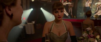 Movie still from “Mrs. Harris Goes to Paris” (2022), directed by Anthony Fabian – A beautiful woman in a dress holding a glass of champagne; Close Up shot, Over the shoulder angle