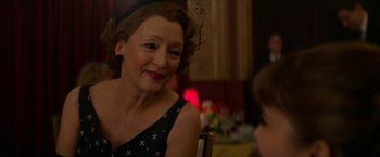 Movie still from “Mrs. Harris Goes to Paris” (2022), directed by Anthony Fabian – An older woman sitting at a table with a young boy; Close Up shot, Over the shoulder angle