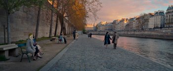 Movie still from “Mrs. Harris Goes to Paris” (2022), directed by Anthony Fabian – People walking along a cobblestone path near a river; Extreme Wide shot, High angle
