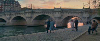Movie still from “Mrs. Harris Goes to Paris” (2022), directed by Anthony Fabian – Two people standing on the side of a bridge; Wide shot, High angle