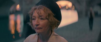 Movie still from “Mrs. Harris Goes to Paris” (2022), directed by Anthony Fabian – An older woman wearing a black hat and a white shirt; Close Up shot, Over the shoulder angle