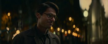 Movie still from “Mrs. Harris Goes to Paris” (2022), directed by Anthony Fabian – A man wearing glasses and a brown jacket; Close Up shot, Over the shoulder angle