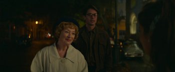 Movie still from “Mrs. Harris Goes to Paris” (2022), directed by Anthony Fabian – A man and a woman standing next to each other in front of a building; Medium shot, Over the shoulder angle