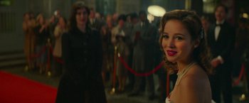 Movie still from “Mrs. Harris Goes to Paris” (2022), directed by Anthony Fabian – A woman standing in front of a crowd of people; Close Up shot, Over the shoulder angle