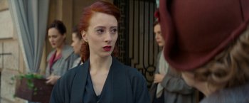 Movie still from “Mrs. Harris Goes to Paris” (2022), directed by Anthony Fabian – A woman with red hair and a black jacket looking to her left; Close Up shot, Over the shoulder angle