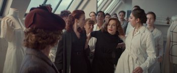 Movie still from “Mrs. Harris Goes to Paris” (2022), directed by Anthony Fabian – Two women in a crowd of people; Medium shot, Over the shoulder angle