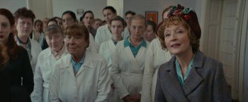 Movie still from “Mrs. Harris Goes to Paris” (2022), directed by Anthony Fabian – A group of women in white lab coats standing in a room; Medium shot, Low angle