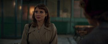 Movie still from “Mrs. Harris Goes to Paris” (2022), directed by Anthony Fabian – A woman in a brown coat standing in front of a building; Close Up shot, Over the shoulder angle