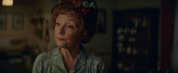 Movie still from “Mrs. Harris Goes to Paris” (2022), directed by Anthony Fabian – An older woman wearing a hat and looking to her left; Close Up shot, Over the shoulder angle