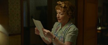 Movie still from “Mrs. Harris Goes to Paris” (2022), directed by Anthony Fabian – An older woman holding a piece of paper in her hands; Close Up shot, Over the shoulder angle