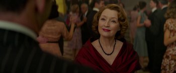 Movie still from “Mrs. Harris Goes to Paris” (2022), directed by Anthony Fabian – An older woman wearing a red dress and a black necklace; Close Up shot, Over the shoulder angle